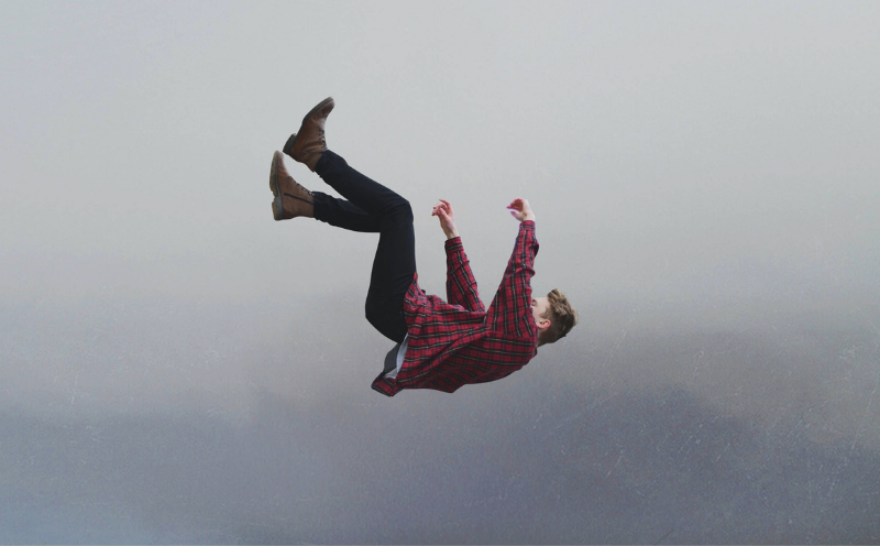 A young man, casually dressed, failling through the sky